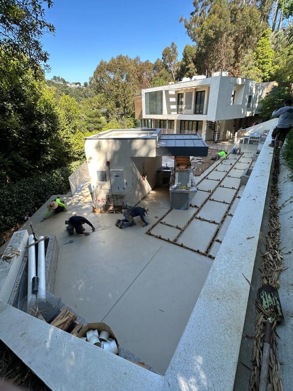Our crew hand-troweling a freshly poured concrete patio on a wooded hillside lot