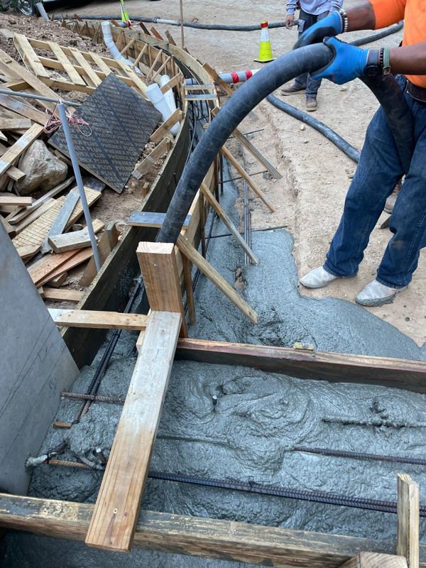 Concrete being pumped into a rebar-reinforced form for a curved wall footing