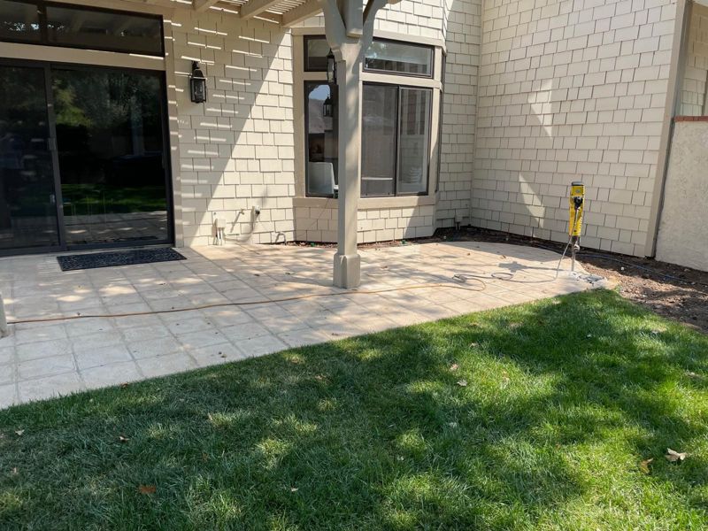 The original tile patio and lawn behind a cream shingle house, before work began