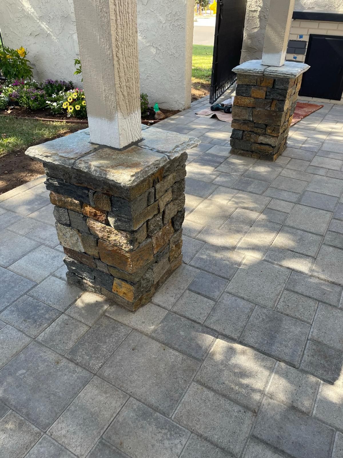 Two stacked-stone column bases with flagstone caps on a paver patio
