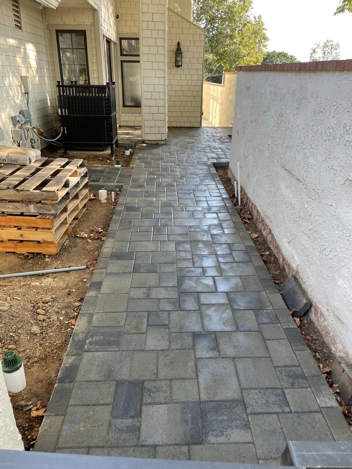 Newly laid charcoal and gray paver side walkway along a shingle house