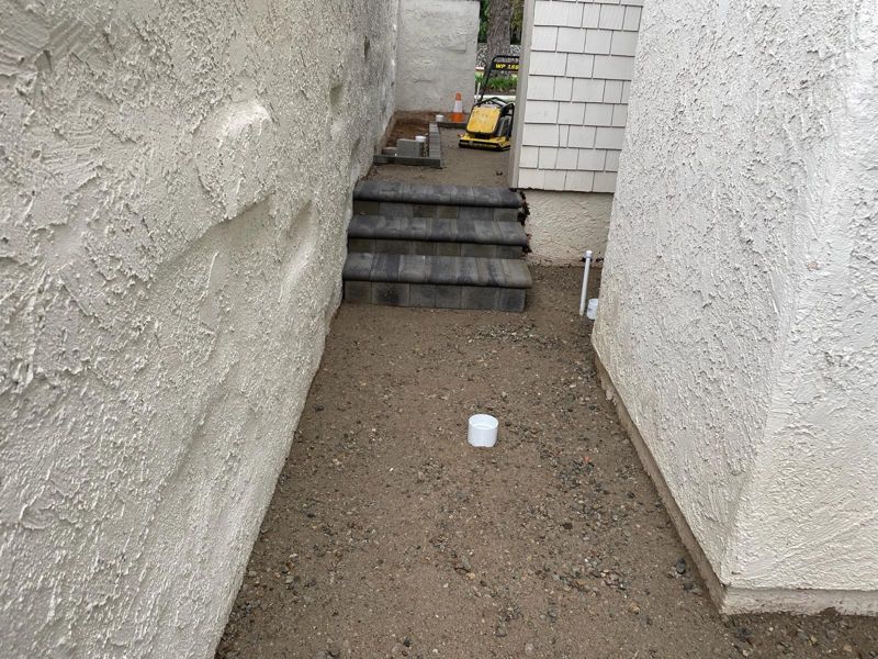 Three new paver steps built into a slope between two stucco walls