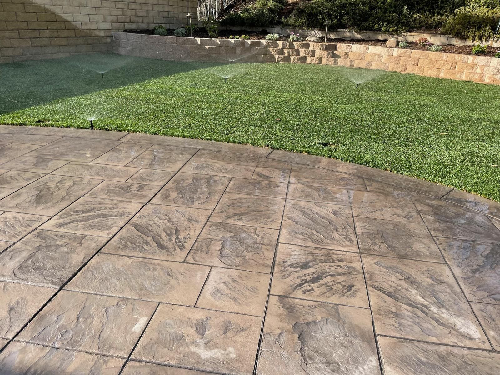 Close view of an ashlar-slate stamped concrete patio beside new sod