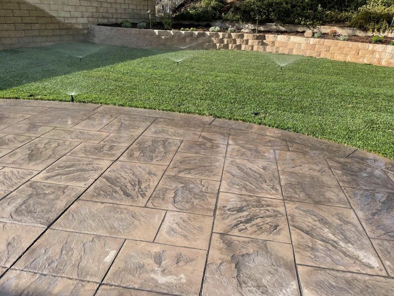 Close view of an ashlar-slate stamped concrete patio beside new sod