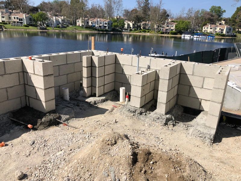 Concrete block walls going up at the edge of a lake, with rebar and gravel fill