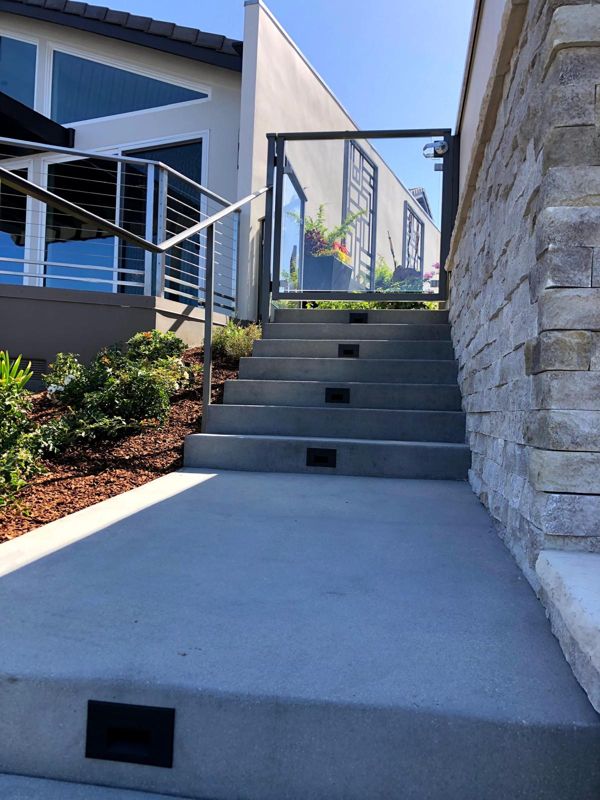 Poured concrete side-yard stairs with recessed step lights, cable railing and a stacked-stone wall