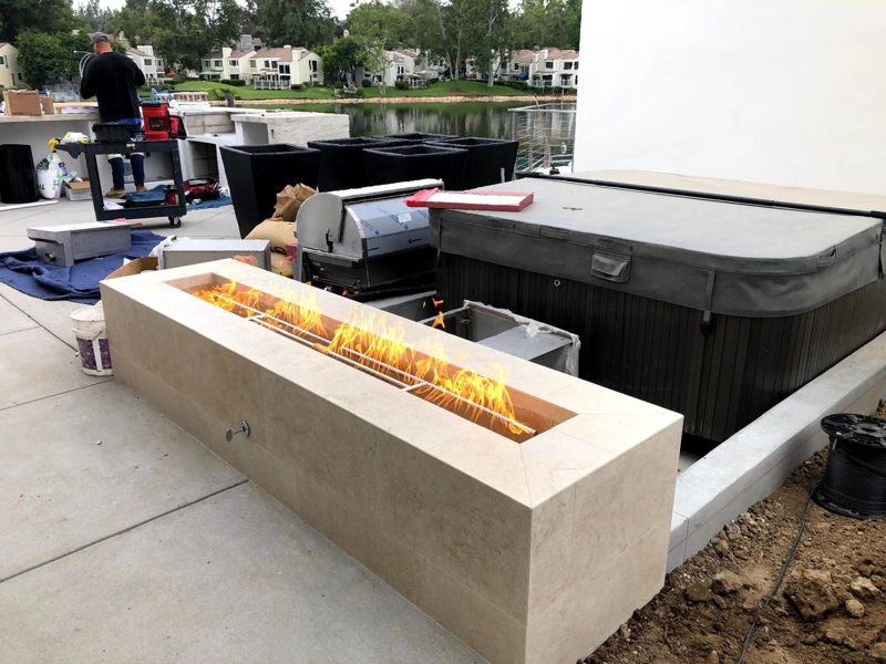 Linear travertine fire pit test-fired mid-build, with materials still on site