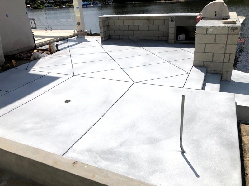 Freshly finished diagonal-scored concrete patio with an unfinished block outdoor kitchen island