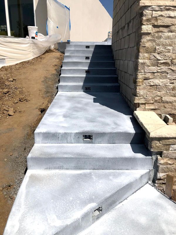 Freshly poured concrete stairs and landing beside a stacked-stone wall